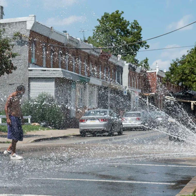 A fire hydrant sprays water in Kensington during a heat wave last July. In Philly's low-income neighborhoods, more than three-quarters of people say they struggle to pay their summer utility bills, but some help exists for certain households without air-conditioning.