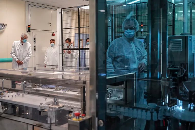 In this June 16 photo, French President Emmanuel Macron listens to a researcher as he visits an industrial development laboratory at French drugmaker's vaccine unit Sanofi Pasteur plant in Marcy-l'Etoile, near Lyon, central France.