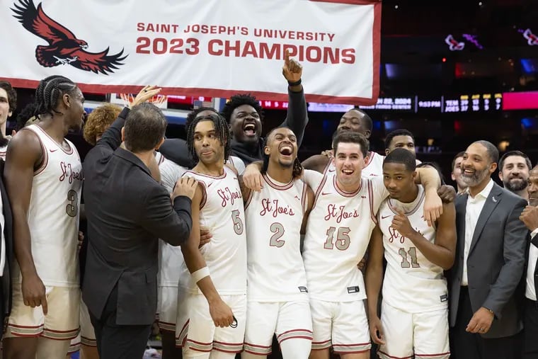 St. Joseph's players celebrates as the championship banner is lowered behind them after they defeated Temple 74-65 to win the Big 5 Classic on Dec. 2, 2023 at the Wells Fargo Center.