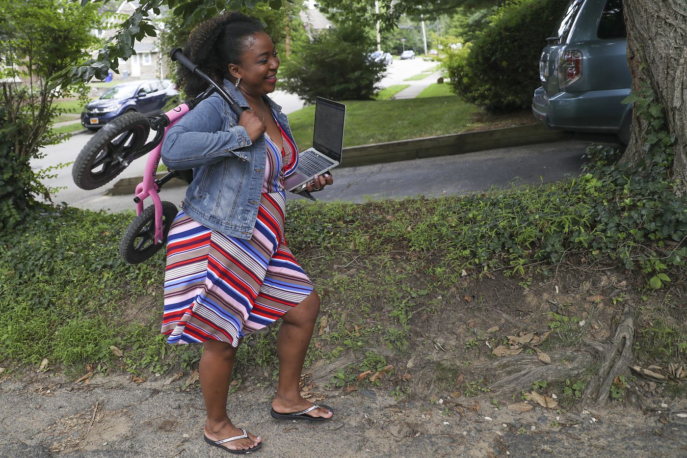 Bethany Watson-Ostrowski carries both her daughters's bicycle that she left behind along with a work laptop outside of her Cheltenham home.