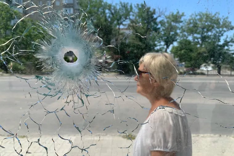 A patron waiting at a bus stop in Mykolaiv on Saturday not far from where a Russian cluster bomb — a projectile made up of small bomblets filled with metal shards — landed a day earlier. Seven civilians were killed and 17 injured in Friday's shelling.