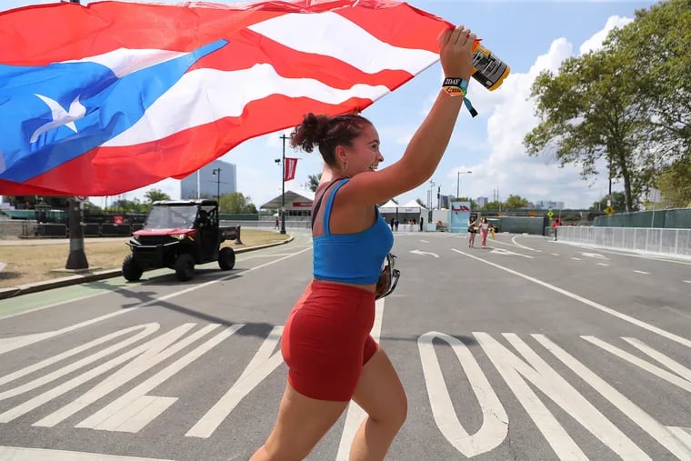 Michelle Alvarado, of North Jersey, runs to the main stage holding a Puerto Rican flag during Day 2 of Made in America.