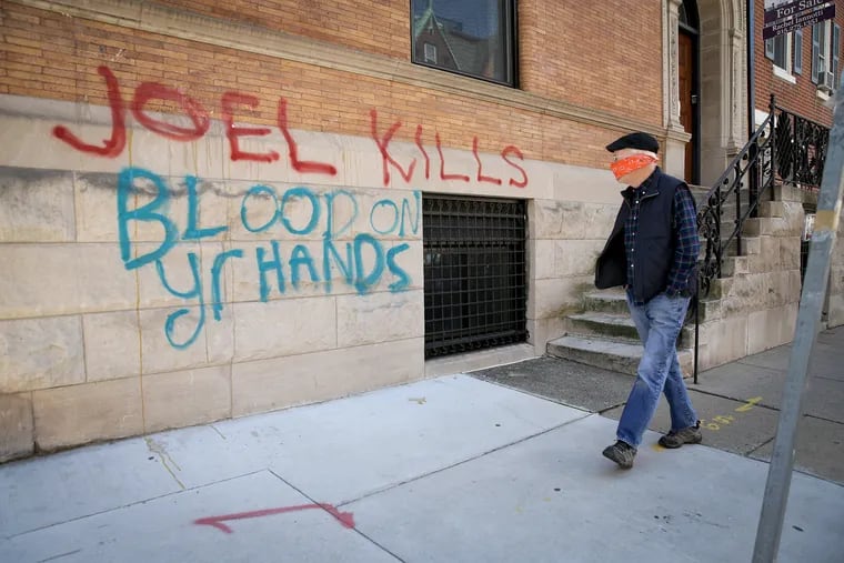 An unidentified pedestrian passes the vandalized home belonging to Joel Freedman at 21st and Locust Streets in Philadelphia, PA on April 6, 2020. Freedman is the owner of Hahnemann University Hospital.