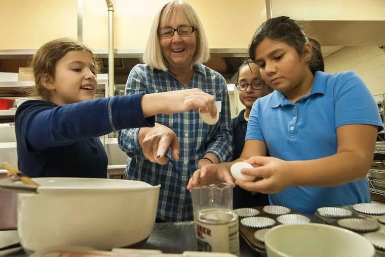 At Loesche Elementary, volunteer Jane Pupis and fifth graders (from left) Natasha Carvalho, Monika Mistry, and Andrea Cuadra make corn muffins.