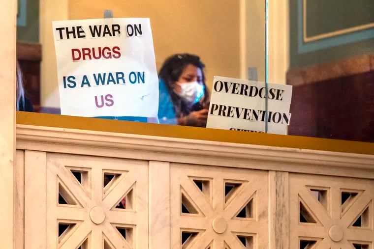 Demonstrators and signs in the overflow balcony in the chamber as Philadelphia City Council met on Sept. 14. They were against a bill to prohibit supervised drug consumption sites across most of the city.