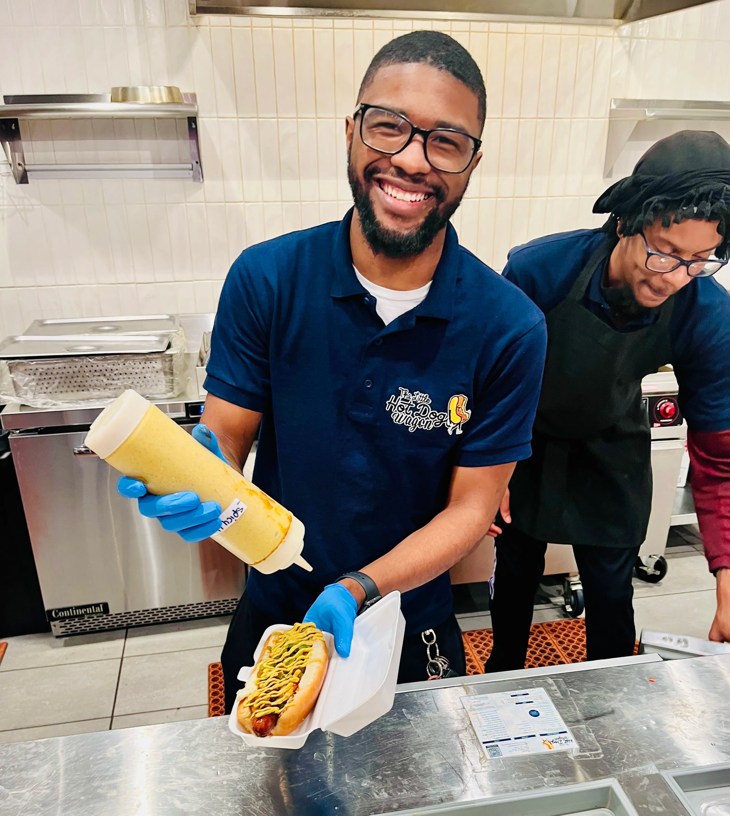 A Little Hot Dog Wagon worker serves up a custom-order hot dog in the Fashion District.