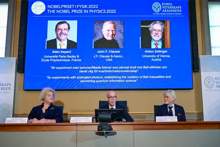 Secretary General of the Royal Swedish Academy of Sciences Hans Ellegren, centre, Eva Olsson, left and Thors Hans Hansson, members of the Nobel Committee for Physics announce the winner of the 2022 Nobel Prize in Physics, from left to right on the screen, Alain Aspect, John F. Clauser and Anton Zeilinger, during a press conference at the Royal Swedish Academy of Sciences, in Stockholm, Sweden, on Tuesday.