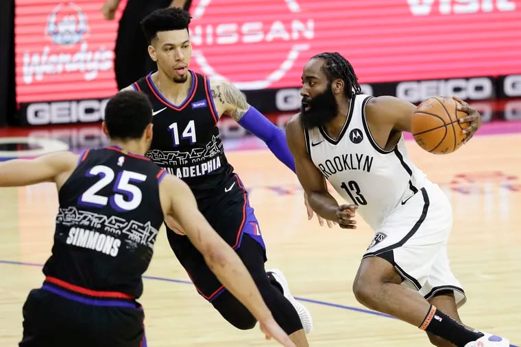 Nets guard James Harden (right) drives to the basket in a game against the Sixers last February as Ben Simmons and Danny Green try to stop him.