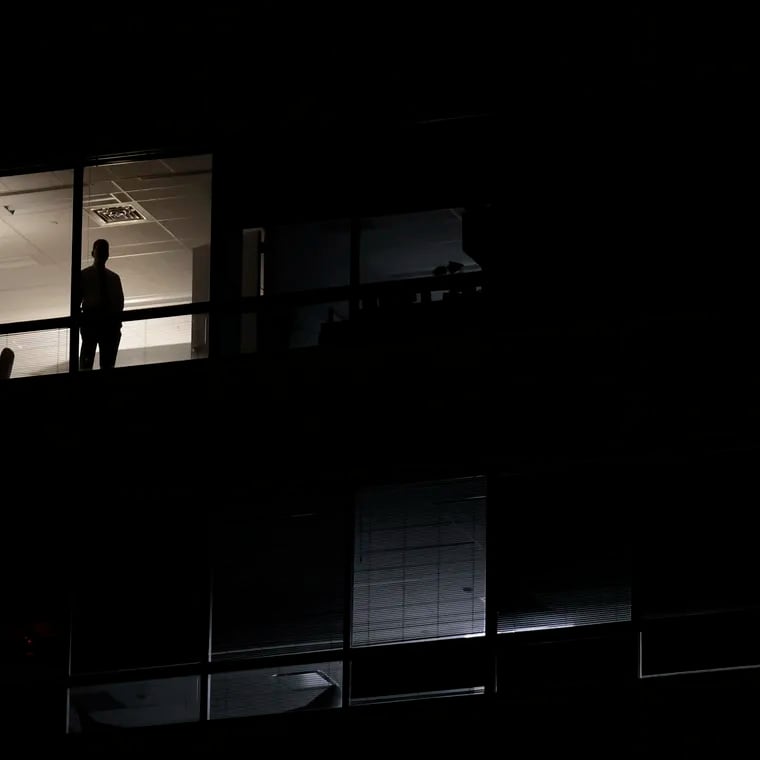 From an adjacent office building, a person watches the scene on Independence Mall prior to the presidential debate at the National Constitution Center.