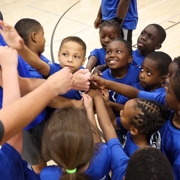 Kids gather in a huddle following a round of basketball drills during Healthy Hoops at the Columbia North YMCA in Philadelphia on Tuesday, July 23, 2024. Healthy Hoops combines a basketball camp with health education. This session of Healthy Hoops focused on asthma education.