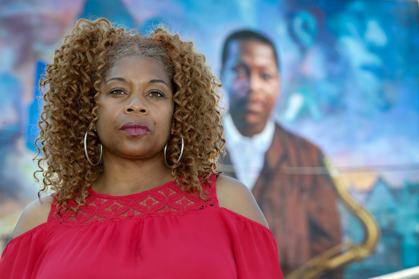 Tonnetta Graham, executive director of the Strawberry Mansion CDC, in front of the mural of musician John Coltrane in Philadelphia.