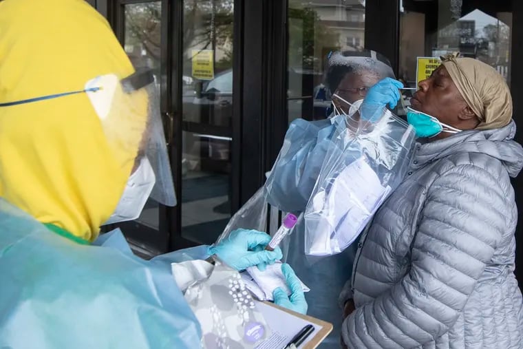 Health care workers administer a Coronavirus test on a woman at a testing site outside the Mt. Airy Church of God in Christ in Philadelphia.