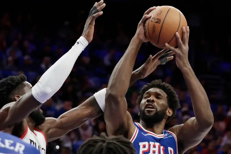 Sixers center Joel Embiid is fouled by Portland's Deandre Ayton (left) in the opening minutes Sunday night.