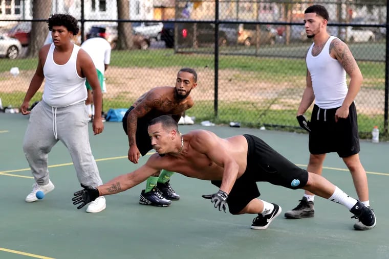 Jacob Catala, center, dives to hit the ball during a doubles handball match at the the courts In Hunting Park along N. 9th St. on Sept. 16, 2022.