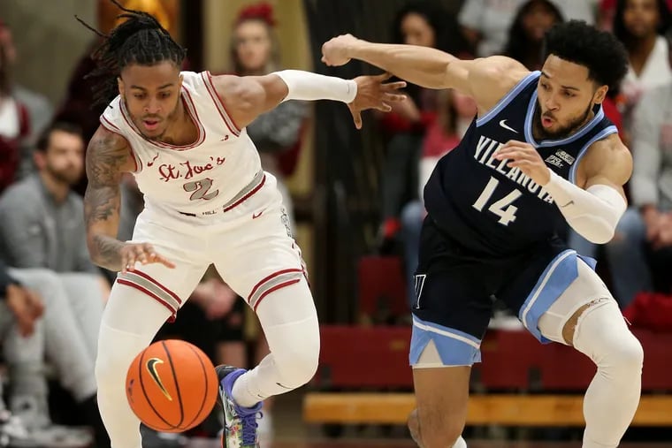 Erik Reynolds (left) of St. Joseph's and Caleb Daniels of Villanova go after a loose ball during the second half between both teams inside Hagan Arena on Saturday.