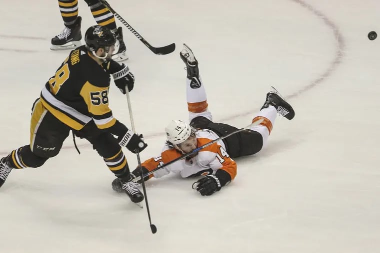 Sean Couturier dives for the puck as Pittsburgh’s Kris Letang get off a shot in the Flyers’ 5-1 win in Game 2. Couturier’s status for Game 4 is unknown.