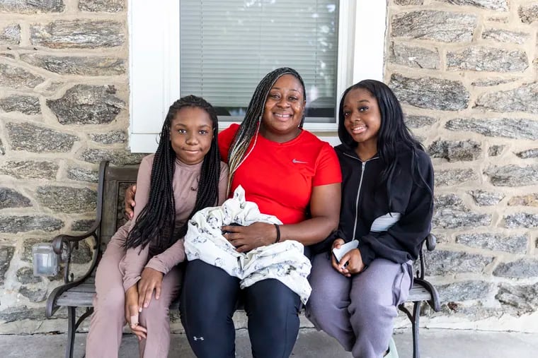 Elauda Seawright, 39, of Elkins Park, a Philadelphia police officer in the 16th District, takes a group photo with her daughters Elasia Grisson, 12, (left) and Ananda Grisson, 18, (right) at their new home in Philadelphia on Tuesday, Aug. 15, 2023. Seawright lost her home to an electrical fire in the basement of her house.