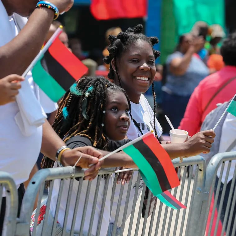 Alanna Bynes, 10, and her mom Alicia Jeremiah, of West Philly, wave flags and watch the Philadelphia Juneteenth Parade and Festival in West Philadelphia, Pa. on Sunday, June 18, 2023. The first Philadelphia Juneteenth Parade and Festival was in 2016. Juneteenth commemorates the end of slavery in the United States. In 2021 President Joe Biden named Juneteenth, celebrated on June 19, a federal holiday.