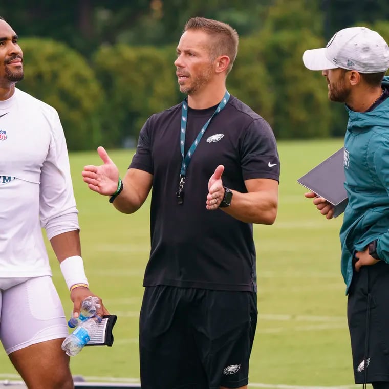 Eagles quarterback Jalen Hurts, left, talks with vice president of player performance Ted Rath, center, and offensive coordinator Shane Steichen, right, during practice at NFL football training camp, Thursday, July 29, 2021, in Philadelphia. (AP Photo/Chris Szagola)