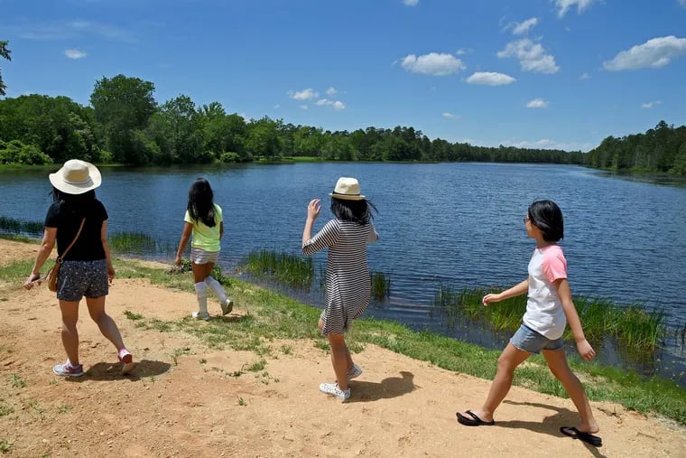 File: A family walks along Batsto Lake, part of Wharton State Forest, in Hammonton, N.J. The state plans to begin charging a $5 per car entrance fee at the Batsto visitor center starting July 1, 2024, after a three-year hiatus.