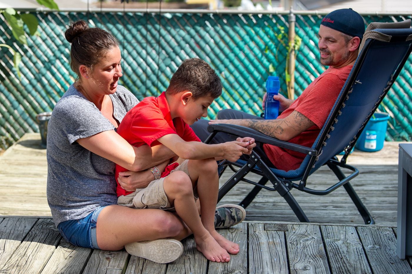 Keri Akkawi holds her son Girius Akkawi, 9, on the deck of their Conshohocken home, with her partner John Barchard. Girius and his brother Crosby have Fragile X syndrome and autism, and have struggled without in-person school or therapies since March.