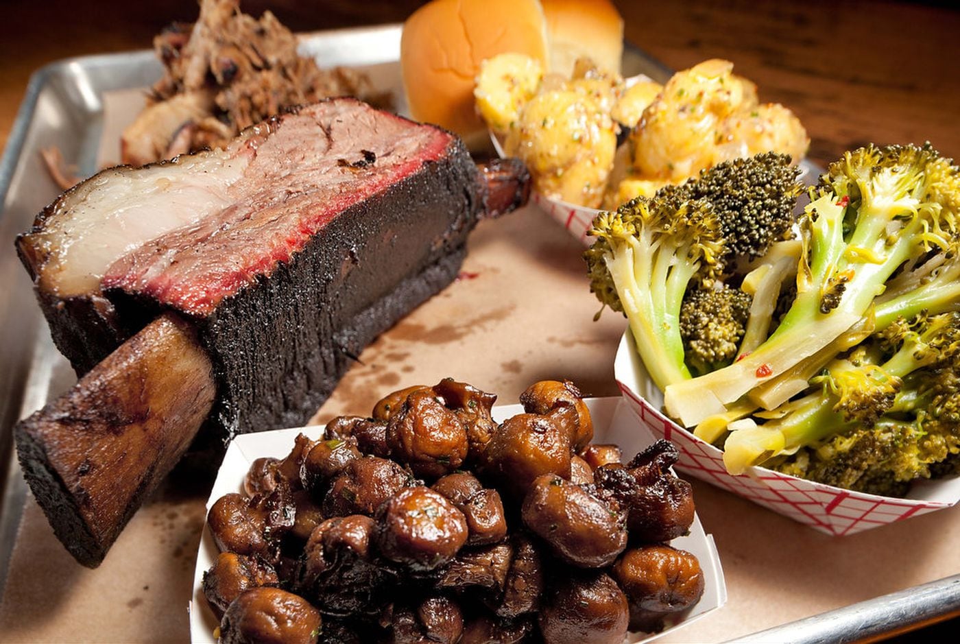 Black Angus bone-in short ribs, Berkshire pulled pork, rolls, German potato salad, broccoli and mushrooms as served at Fette Sau. (David M Warren / Staff Photographer)