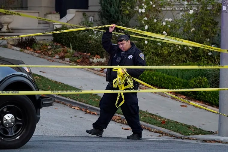 A police officer unfurls yellow tape last Friday on a closed street near the San Francisco home of House Speaker Nancy Pelosi and her husband Paul Pelosi. Paul Pelosi was attacked and severely beaten by an assailant with a hammer who broke into their home Oct. 28.