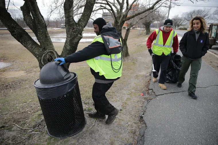 Malcolm Flowers (left) checks a trash can as Cristina "Critt" DeCristofor (right) talks with Kevin Burk while cleaning the area around the Camden County Boathouse in Pennsauken.