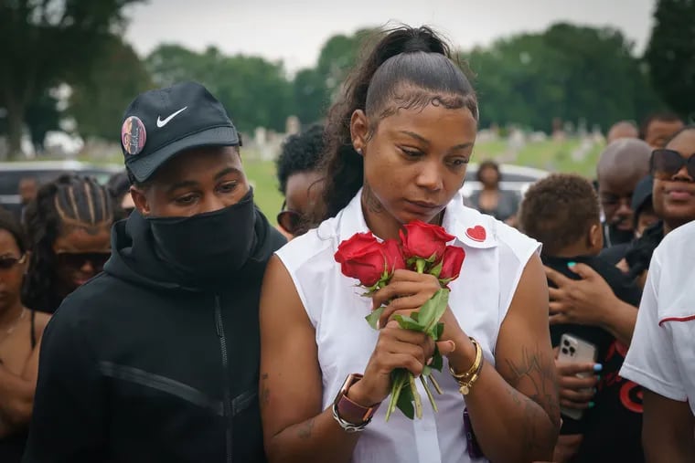 Emily Johnson, center, holds roses at the funeral of her 16-year-old son, K.J., in July 2021.