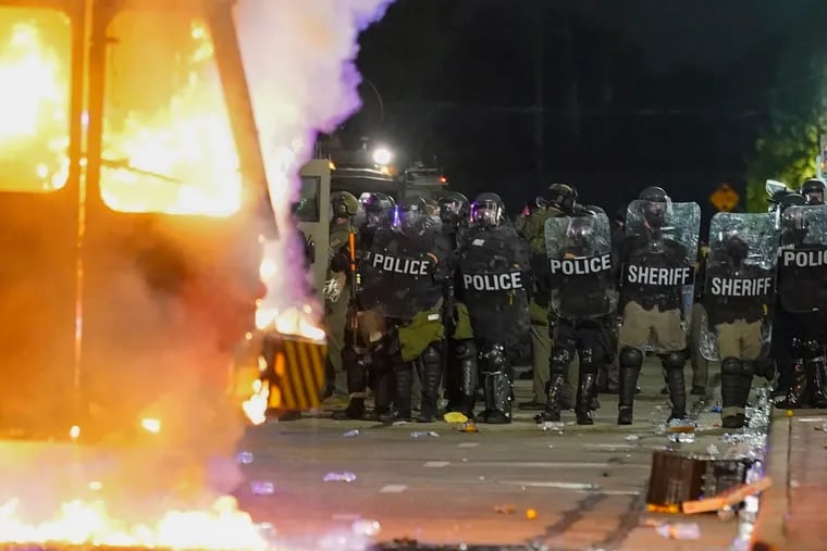 Police stood near a garbage truck that was on fire during protests Monday.