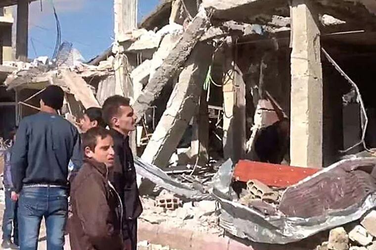 Syrians gather in front of a building destroyed by a car bomb in Qatana, 15 miles southwest of Damascus. State media reported Thursday that bombs had exploded in two suburban districts, killing 24 and wounding dozens. SANA, AP