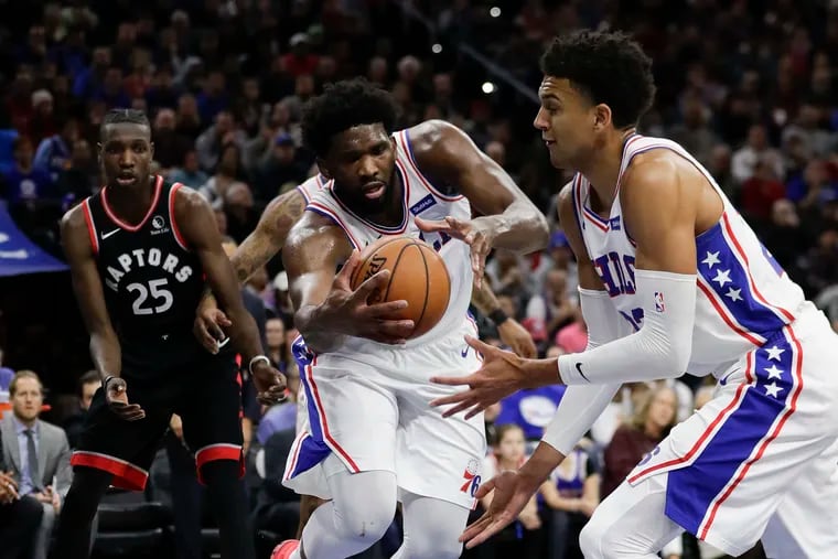 Sixers center Joel Embiid grabs the basketball next to teammate Matisse Thybulle (right) against the Raptors.