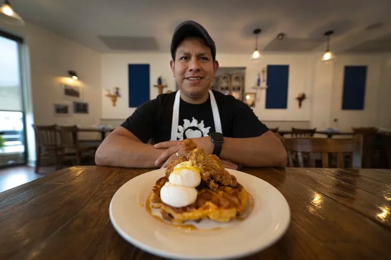 Chef Juan Lopez in On Point Bistro's dining room with a poached egg-topped waffle in 2023.