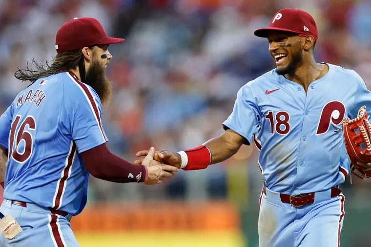 Johan Rojas smiles with teammate left fielder Brandon Marsh after Rojas caught Los Angeles Dodgers Enrique Hernández’s seventh inning hit to left center field.