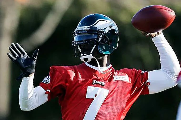 Michael Vick (left) passes as Nick Foles looks on during practice at the team's NFL football training facility, Wednesday, Dec. 19, 2012, in Philadelphia. (Matt Rourke/AP)