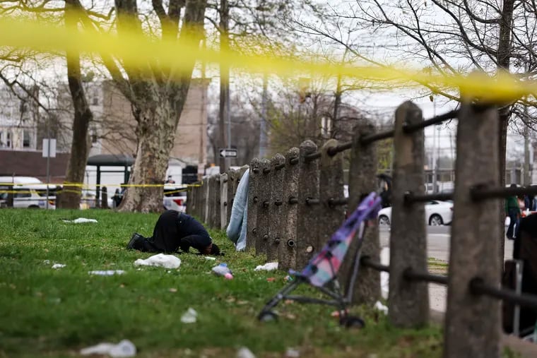 A man kneels in prayer near the crime scene after multiple people were shot at an Eid al-Fitr gathering at Clara Muhammad Square in West Philadelphia.