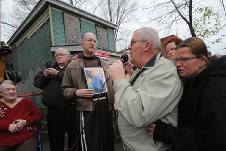 On River Road in Camden, Hargrove Demolition begins to tear down "Ron's House."  Here, Father Jud Weiksnar holds a photo of Ron Hurlburt while Donald Russell speaks; at right, Tammy Vega holds on to Russell and becomes emotional; she is Hurlburt's daughter. At left are Marge and Father Kent Walmsley. 12/06/11  ( APRIL SAUL / Staff Photographer )