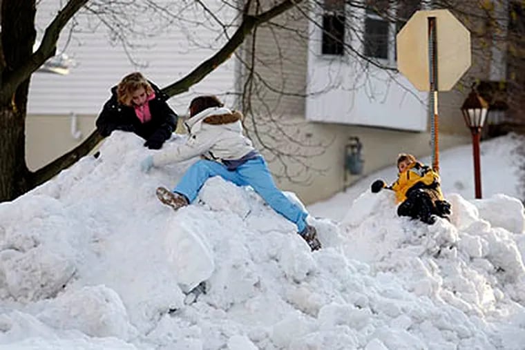 Rachel Mills and Shelby Moore, both 10, and Mitchel Mills, 9, Rachel's brother, took advantage of a snow day and street plowing to form giant snow mountains on Monday, in Claymont, Del. (Ron Cortes / Staff Photographer)