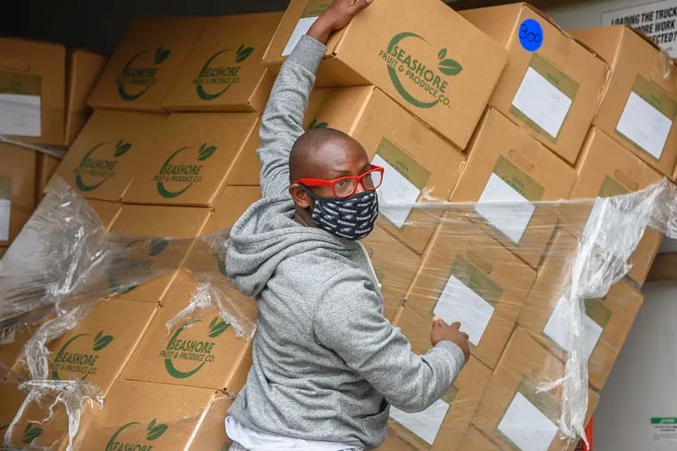 City sanitation worker Terrill Haigler, also known as "Ya Fav Trashman" on Instagram, tends to a stack of toppled boxes during a food drive he organized Saturday in North Philadelphia for frontline workers.