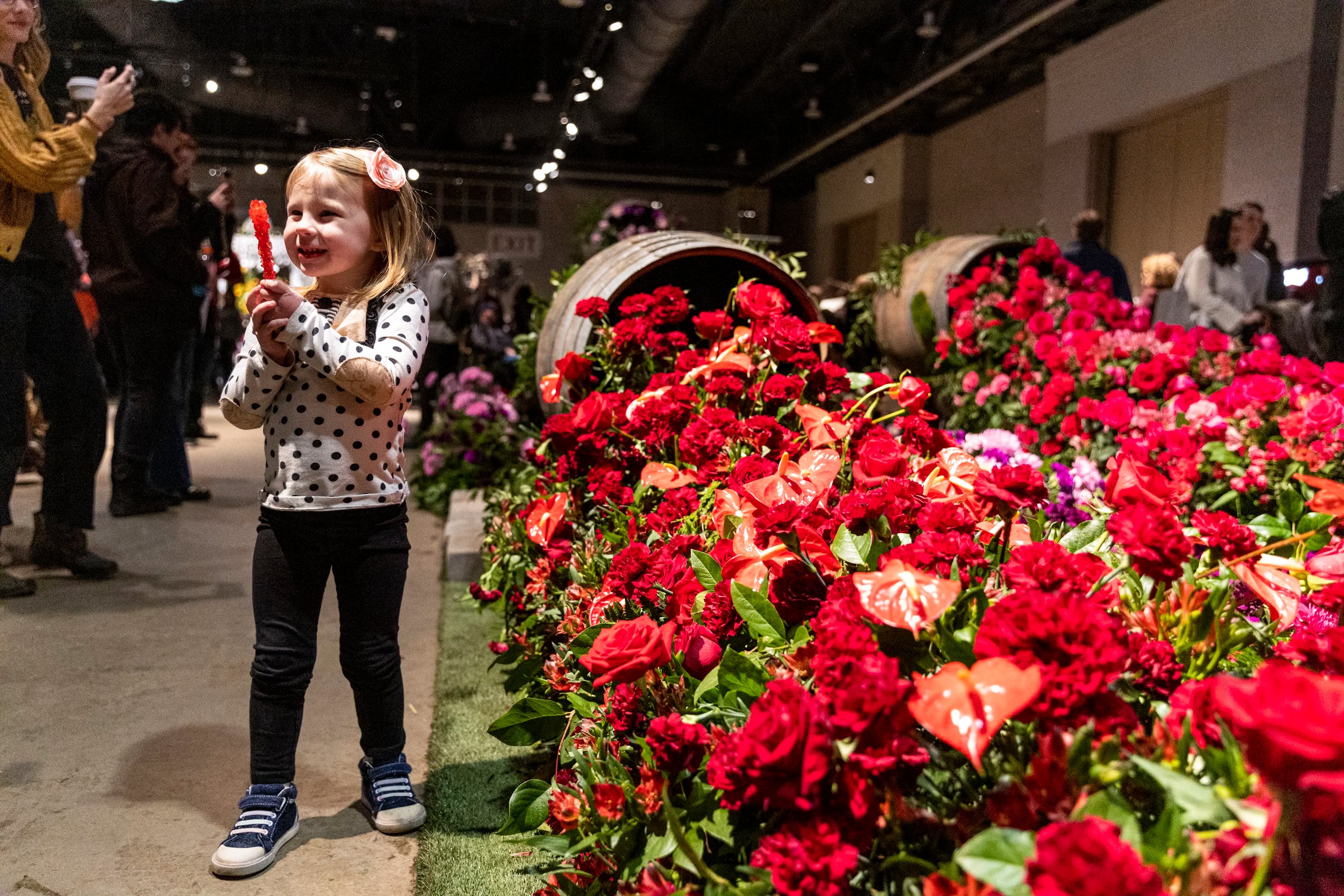 Ella Clark, 3, poses by the United Through Our Pour display by Black Girl Florists, while her mom, Jami Clark, of Narberth, Pa., takes a photo.