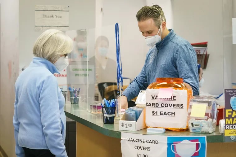 Charlotte Schwartz (left) is checked in by Marc Ost (right), co-owner of Eric's RX Shoppe, to receive her fourth COVID-19 vaccine, at Eric's RX Shoppe Vaccine Clinic in Horsham on Wednesday, Feb. 2, 2022.