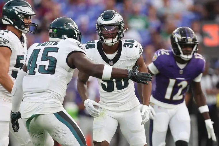 Quinyon Mitchell (right) celebrates after breaking a pass in the first quarter against the Ravens.