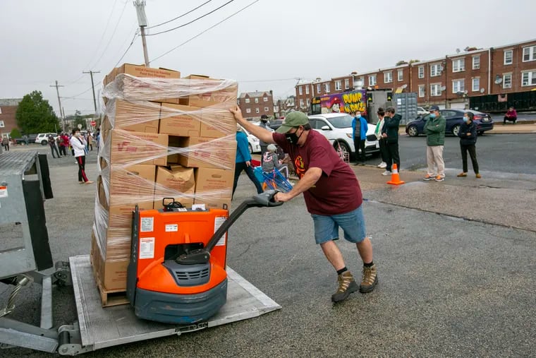 Employee of Share Food Program in Hunting Park drops off supplies to be given away. U.S. median household income declined while poverty increased in 2020.
