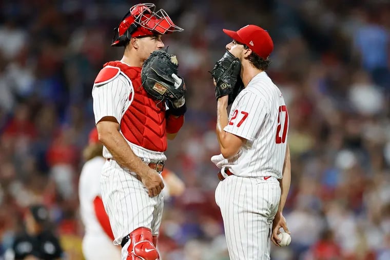 Phillies pitcher Aaron Nola and catcher J.T. Realmuto meet during the third inning against the New York Mets on Friday.