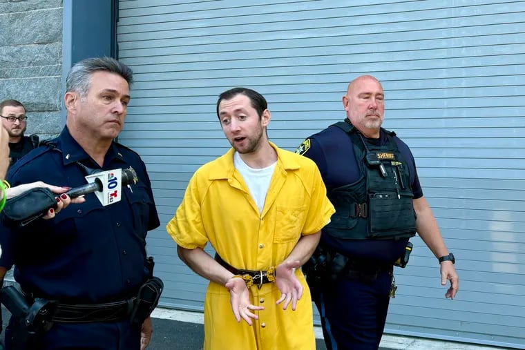 Justin Mohn talks to reporters as he's led out of the Bucks County Justice Center on Tuesday. Mohn, 32, has been charged with first-degree murder in the shooting and beheading of his father.