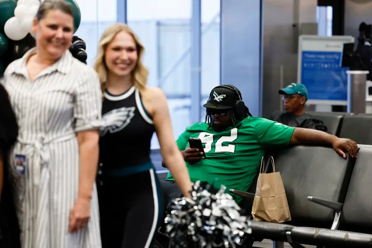 Tahir Basil (right) takes a seat looking at his phone during a Brazilian themed pep rally for Eagles fans leaving for São Paulo, Brazil.