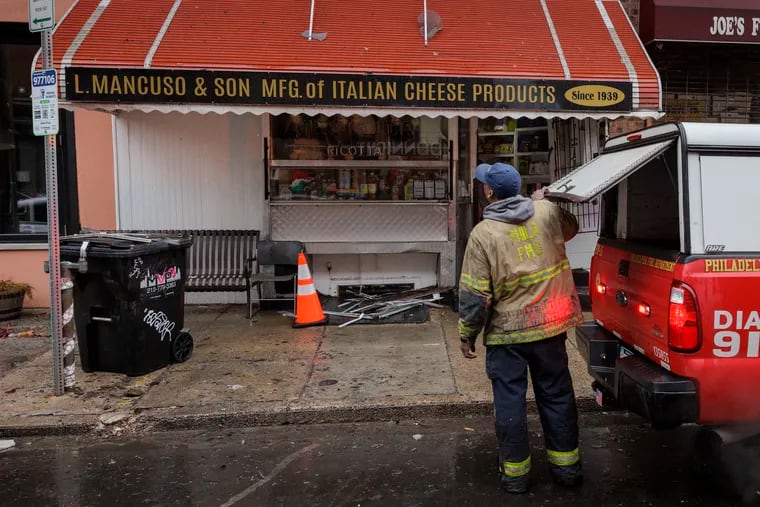 Philadelphia Fire Department investigators look at the fire scene from in front of L. Mancuso & Son along Passyunk Avenue near Mifflin Street. There was a fire in the apartments above the beloved Italian grocery store on Thursday, Jan. 25, 2024.