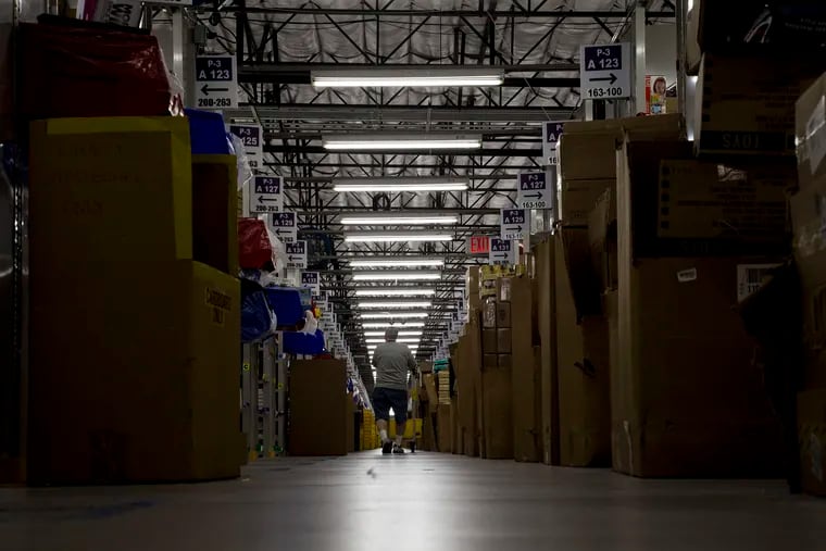 A worker filling an order pushes a cart through aisles of merchandise at an Amazon Fulfillment Center in San Bernardino. (Gina Ferazzi/Los Angeles Times/TNS)