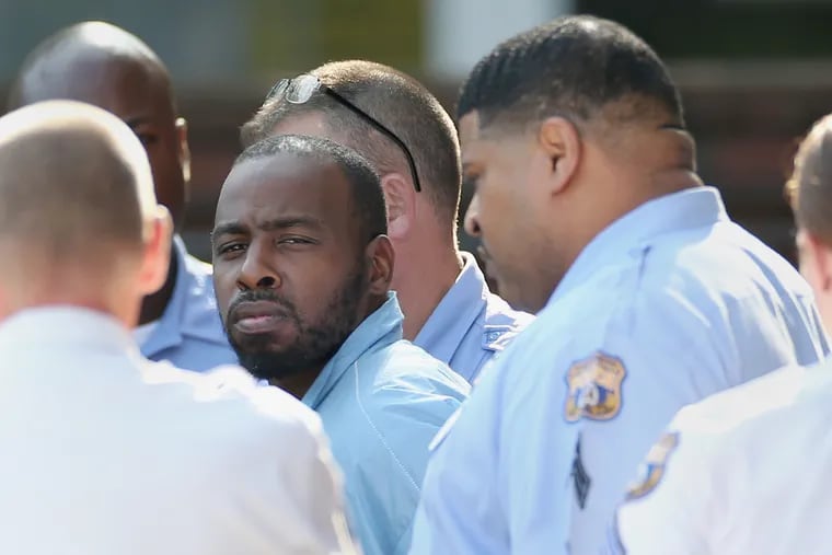 Maurice Hill, accused of shooting six police officers during an hours-long standoff, is led out of the Philadelphia Police Department 1st District station in South Philadelphia after being arraigned in August. Hill surrendered after allegedly barricading himself in a Tioga home for hours and repeatedly firing on officers.