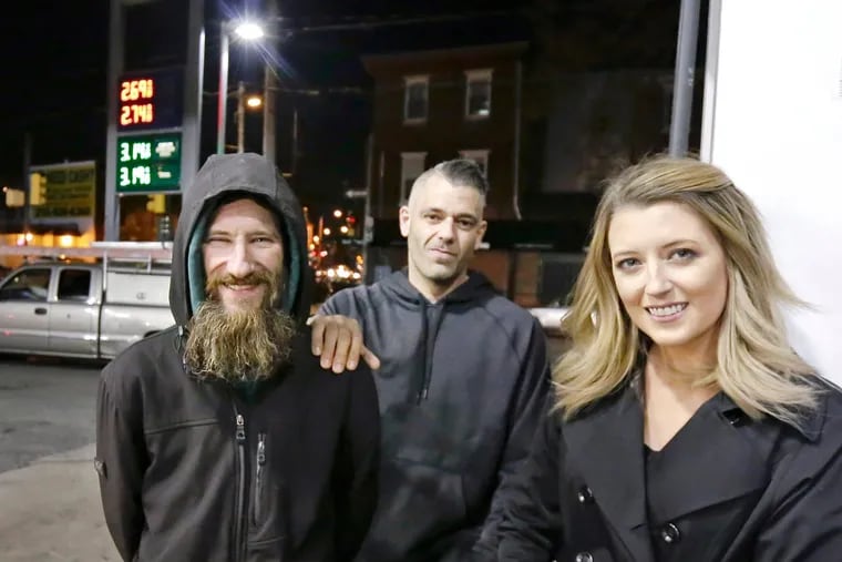 Johnny Bobbitt Jr., left, Kate McClure, right, and Mark D'Amico pose at a Citgo station were they claimed Bobbitt purchased gas for McClure's stranded car.